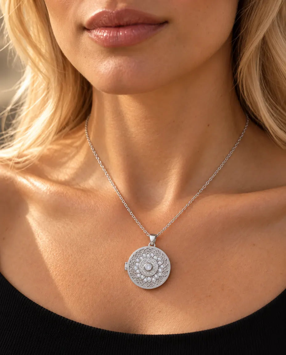Vrouw in een zwarte gebreide top draagt de zilverkleurige ketting met medaillon met mandalabloem