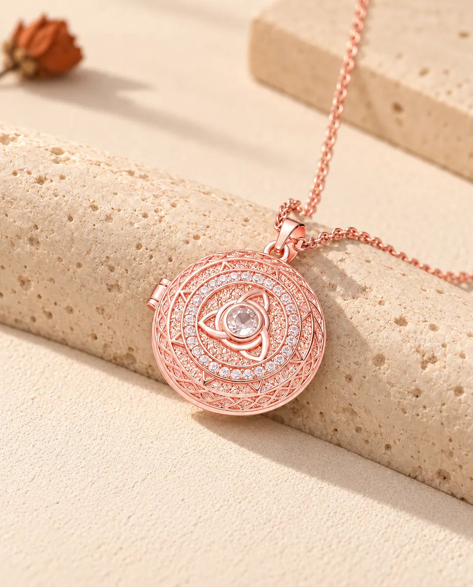 Roségoudkleurig fotomedaillon met triquetra en een ring van zirkonia, rustend op travertin