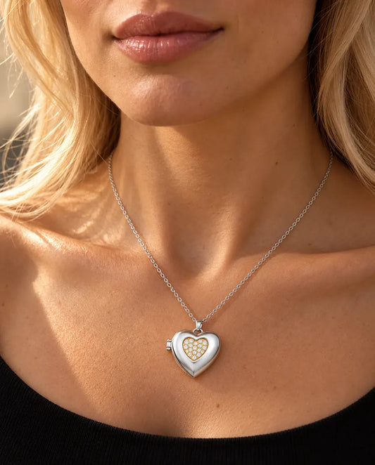 Vrouw in een zwarte gebreide top draagt de ketting met het zilverkleurige hartmedaillon met pavé hartje