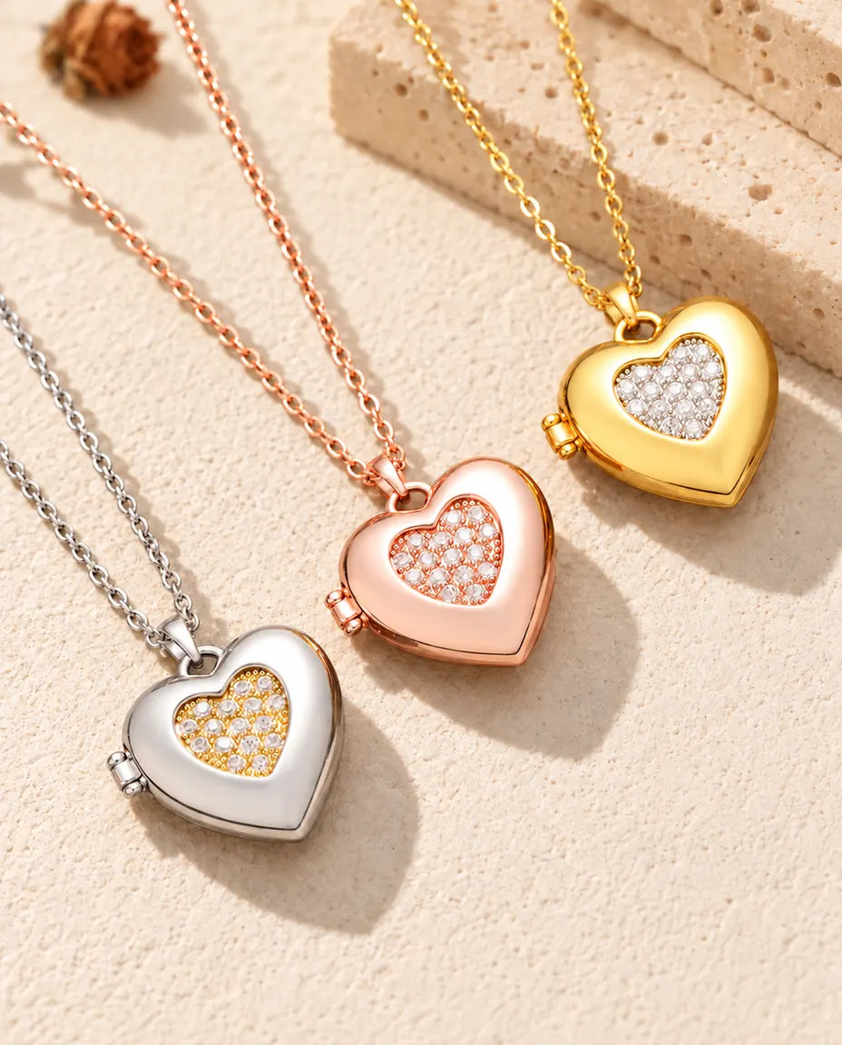 Hartmedaillons met pavé hartje in zilver-, roségoud- en goudkleurig, schuin op crèmekleurig gips