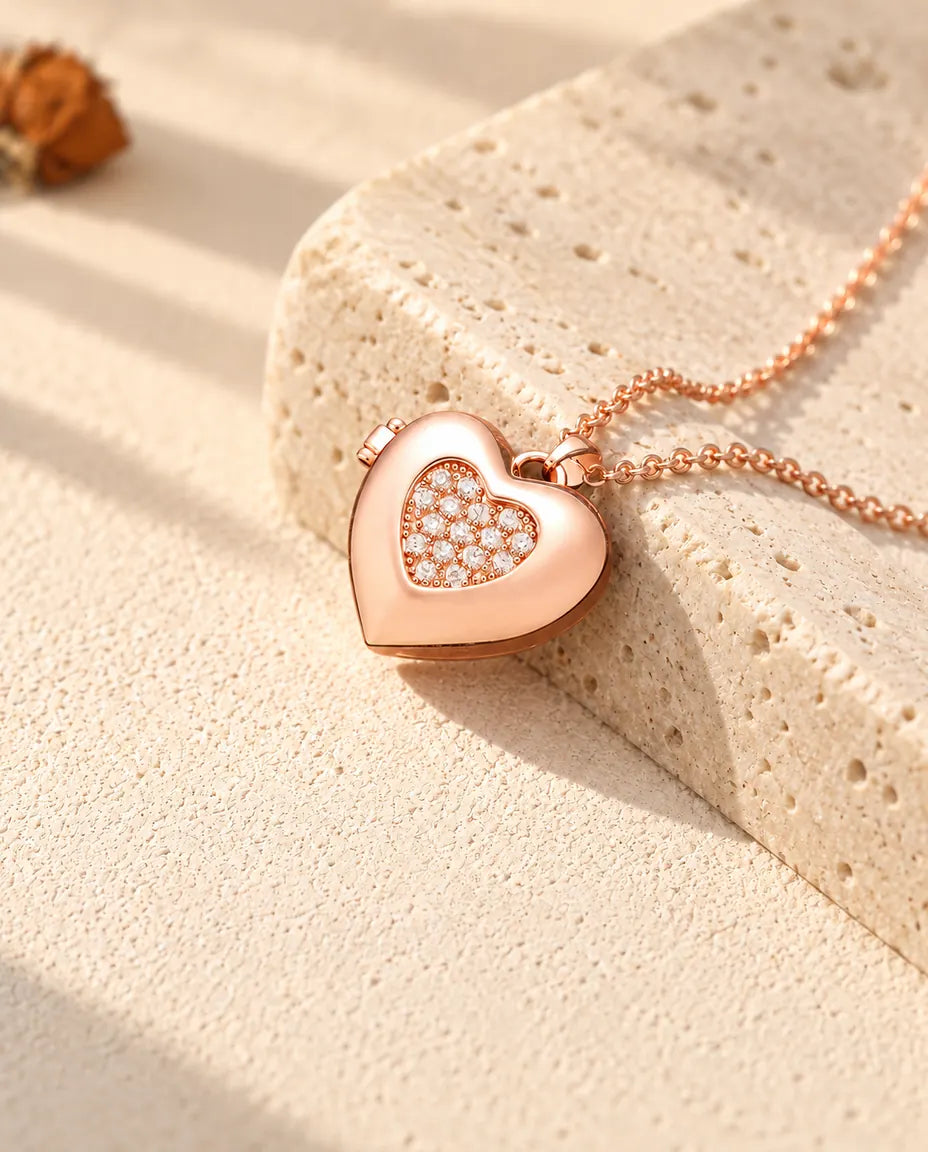 Ketting met een roségoudkleurig hartmedaillon met pavé hartje op travertin in warm zonlicht