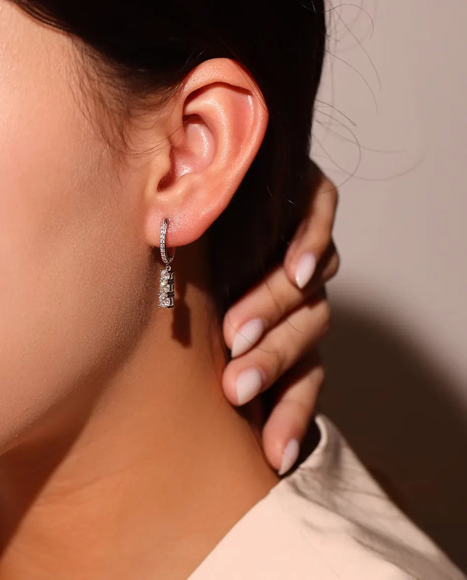 Moissanite Creolen met Drie Hangende Stenen in 925 Sterling Zilver - gedragen in het oor van een model, vingers bij de hals