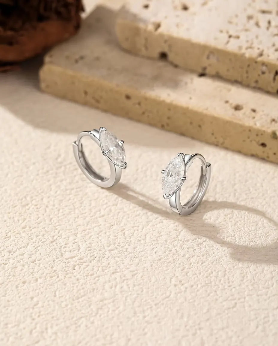 Moissanite Creolen in 925 Sterling Zilver - het paar naast elkaar op een licht gestructureerd oppervlak