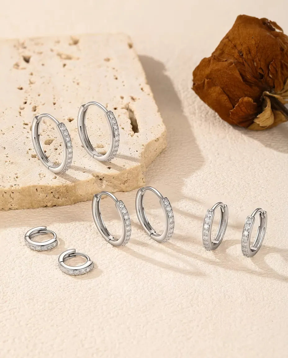 Moissanite Creolen in 925 Sterling Zilver - alle vijf maten op een licht oppervlak bij een travertijnplaat