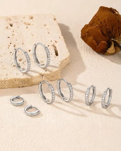 Moissanite Creolen in 925 Sterling Zilver - alle vijf maten op een licht oppervlak bij een travertijnplaat