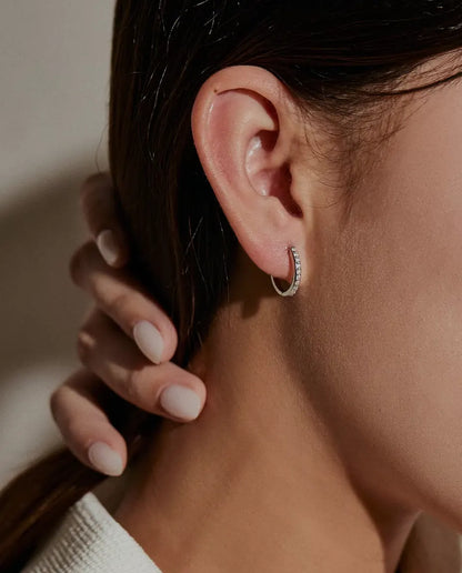 Moissanite Creolen in 925 Sterling Zilver - gedragen in het oor van een model, hand houdt het haar opzij