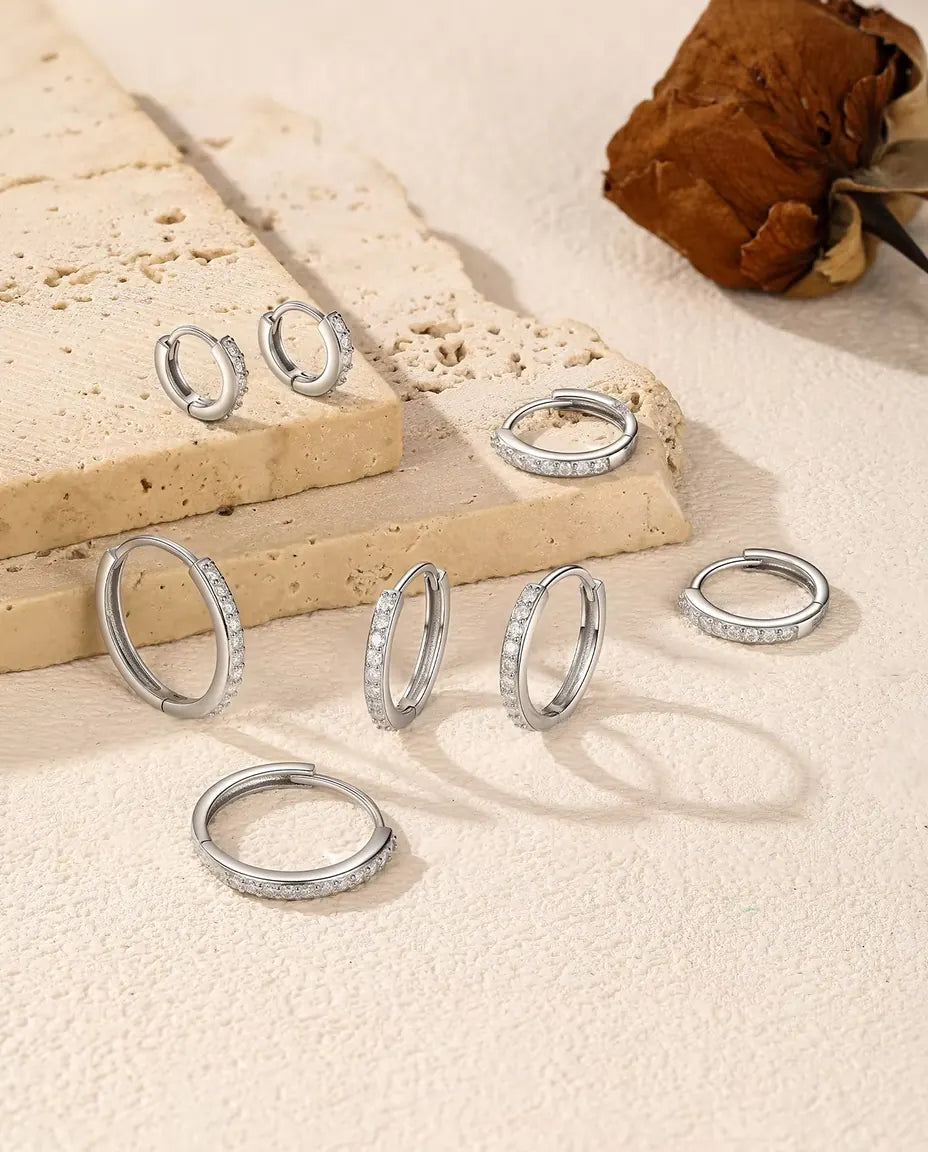 Moissanite Creolen in 925 Sterling Zilver - vijf maten verspreid over een travertijnplaat en een licht oppervlak