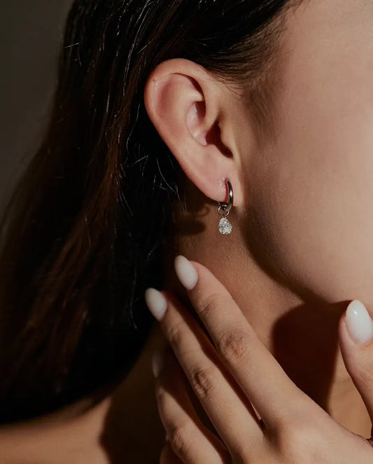 Moissanite Creolen met Peervormige Hanger in 925 Sterling Zilver - gedragen in het oor van een model, hand bij het gezicht