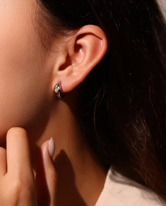Moissanite Huggie Creolen met Asscher Slijpsel in 925 Sterling Zilver - gedragen in het oor van een model, hand bij het gezicht