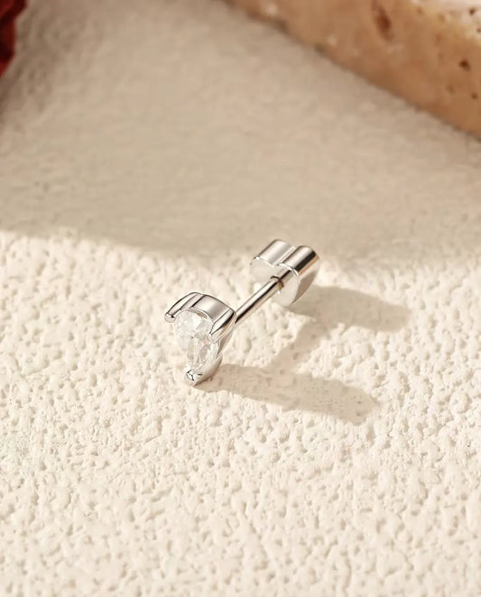 Moissanite Oorknopjes Peervorm met Twee Pootjes in 925 Sterling Zilver - op zijn kant op een licht gestructureerd oppervlak, hartvormig achterkantje op de stift