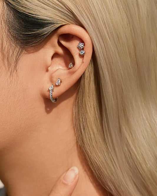 Moissanite Oorknopjes Peervorm met Twee Pootjes in 925 Sterling Zilver - gedragen door een model met haar hand bij haar hals