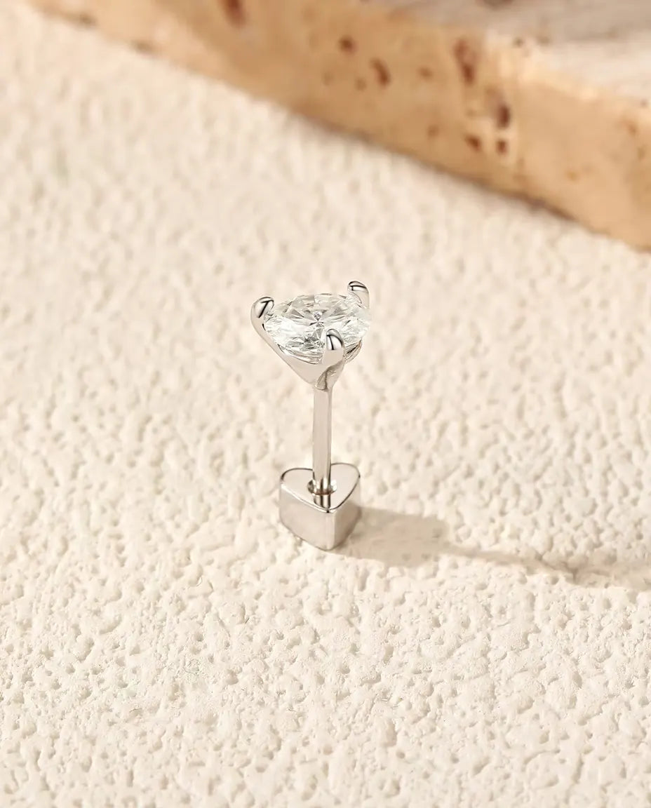 Moissanite Oorknopjes Rond met Drie Pootjes in 925 Sterling Zilver - rechtop op het hartvormige achterkantje, op een licht gestructureerd oppervlak