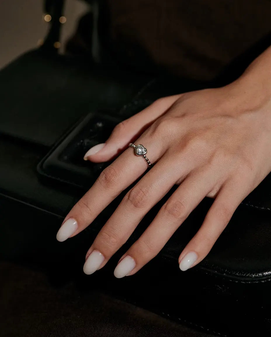 Moissanite Ring met Hart in 925 Sterling Zilver - gedragen aan een hand op een zwarte tas