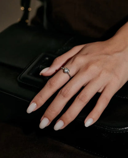 Moissanite Ring met Hart in 925 Sterling Zilver - gedragen aan een hand op een zwarte tas