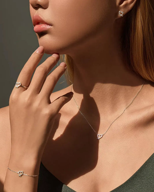 Model draagt de complete moissanite hartjesset: ketting, armband, ring en oorknopjes
