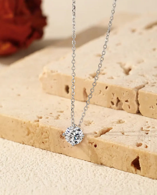 Moissanite Ketting met Solitair van 1 ct in 925 Sterling Zilver - hanger over de rand van een travertijnplaat