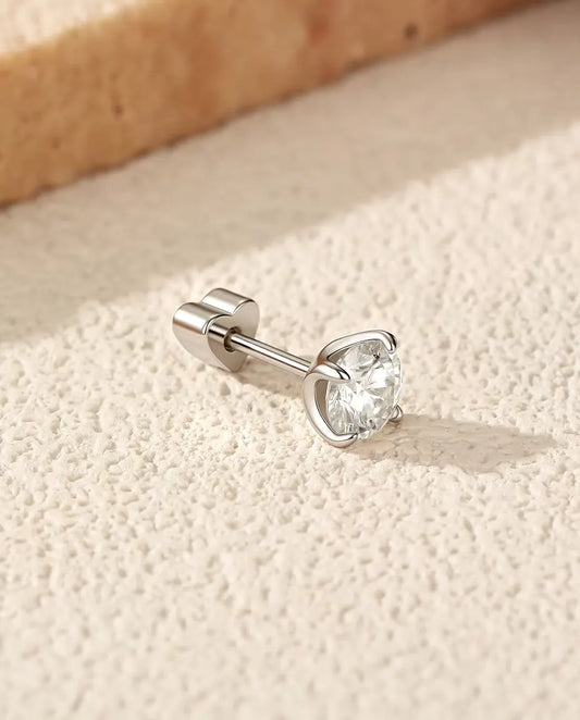 Moissanite Solitair Oorknopjes 5 mm met Vier Pootjes in 925 Sterling Zilver - op zijn kant op een licht gestructureerd oppervlak, hartvormig achterkantje op de stift