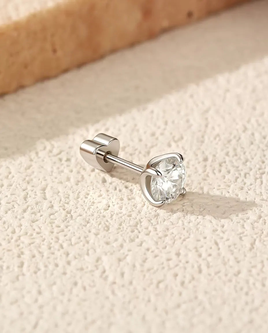 Moissanite Solitair Oorknopjes 5 mm met Vier Pootjes in 925 Sterling Zilver - op zijn kant op een licht gestructureerd oppervlak, hartvormig achterkantje op de stift