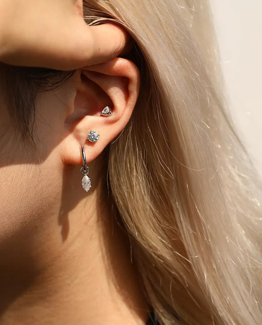 Moissanite Solitair Oorknopjes 5 mm met Vier Pootjes in 925 Sterling Zilver - gedragen door een model dat haar haar achter haar oor strijkt