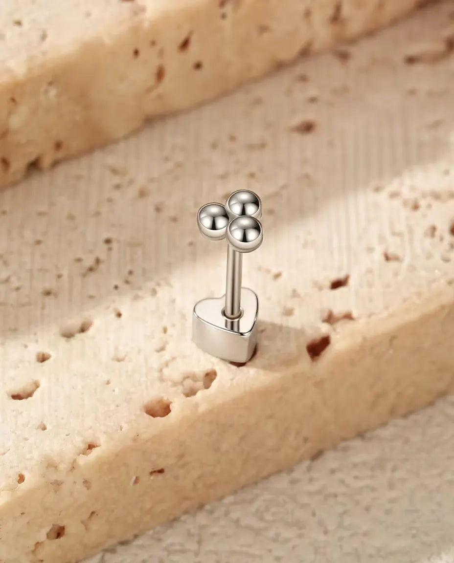 Oorknopjes Klavertje met Drie Bolletjes in 925 Sterling Zilver - rechtop op het hartvormige achterkantje, op een licht gestructureerd oppervlak