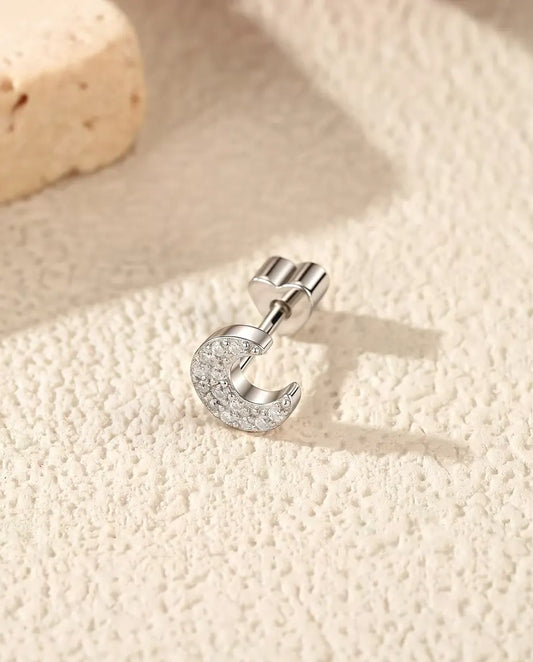 Oorknopjes Maansikkel met Pavé Moissanite in 925 Sterling Zilver - op zijn kant op een licht gestructureerd oppervlak, hartvormig achterkantje op de stift
