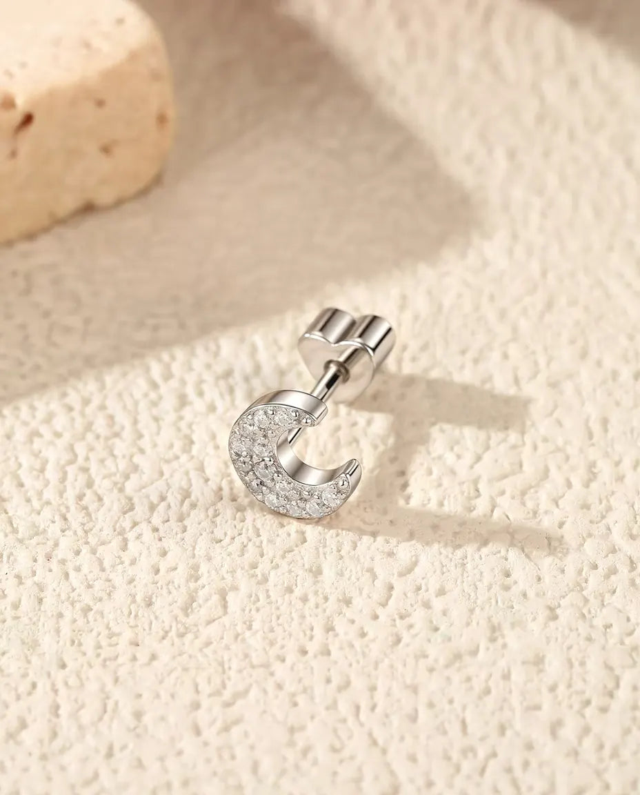 Oorknopjes Maansikkel met Pavé Moissanite in 925 Sterling Zilver - op zijn kant op een licht gestructureerd oppervlak, hartvormig achterkantje op de stift