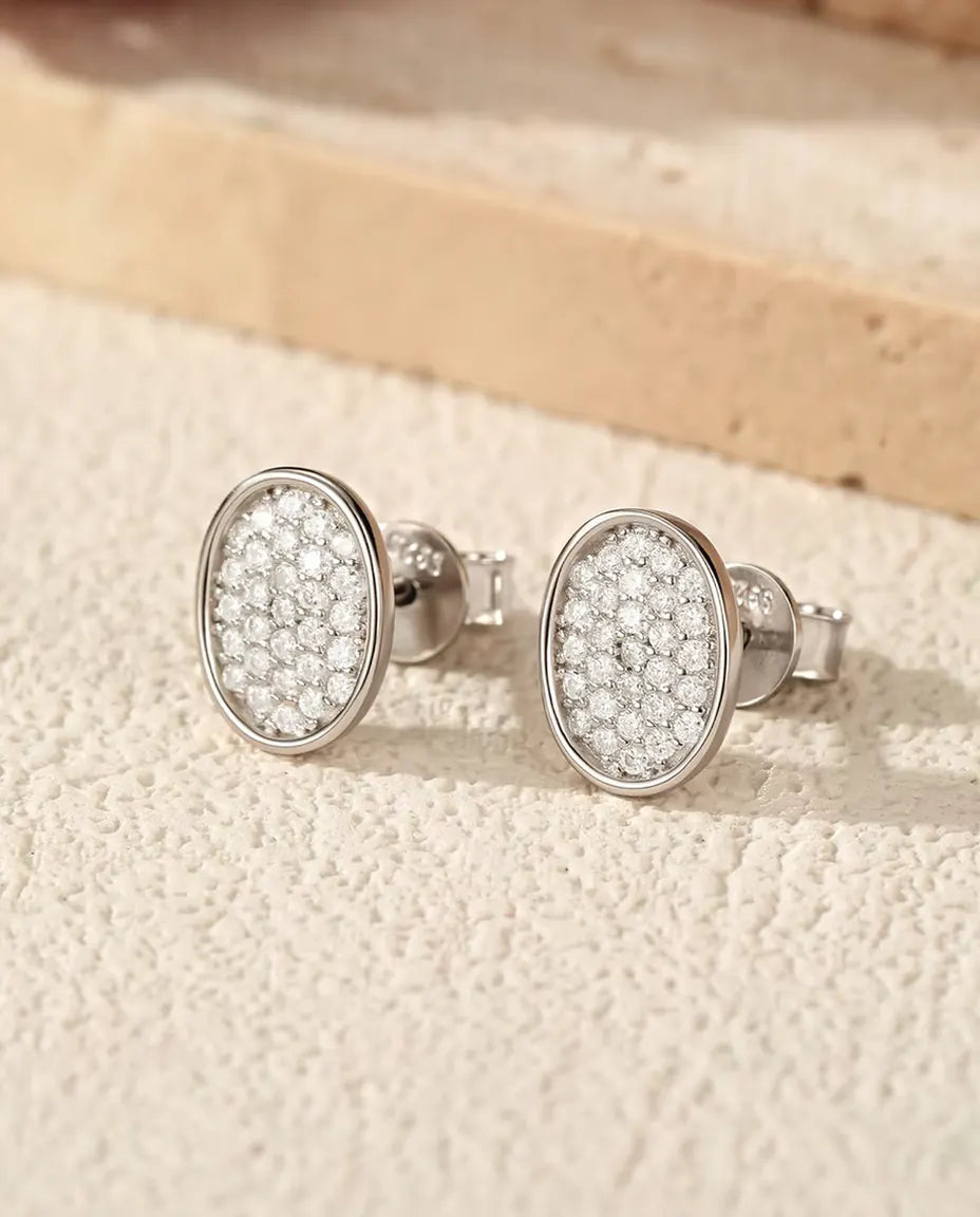 Ovale Pavé Oorknopjes met Moissanite in 925 Sterling Zilver - het paar op een licht gestructureerd oppervlak