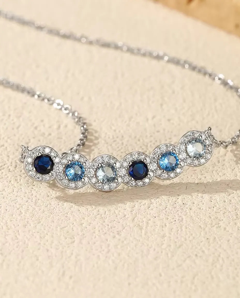 Staafketting Blauw Verloop - zes blauwe stenen met pavé halo, gebogen staaf 34 mm, 925 sterling zilver