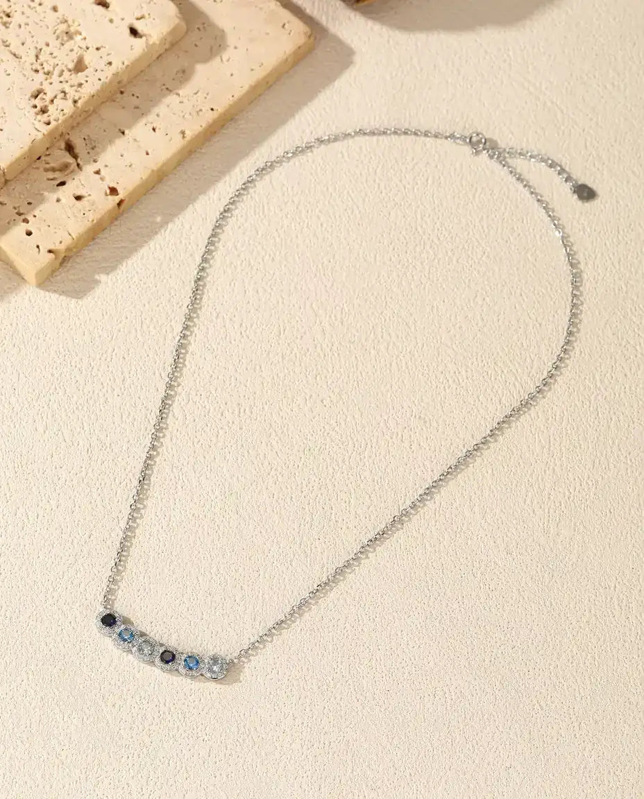 Staafketting Blauw Verloop - zes blauwe stenen met pavé halo, gebogen staaf 34 mm, 925 sterling zilver