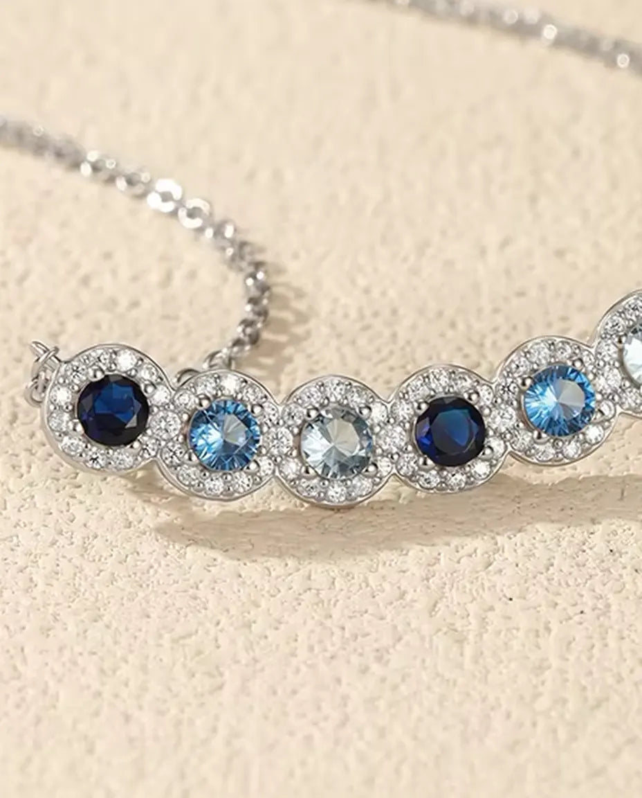 Staafketting Blauw Verloop - zes blauwe stenen met pavé halo, gebogen staaf 34 mm, 925 sterling zilver