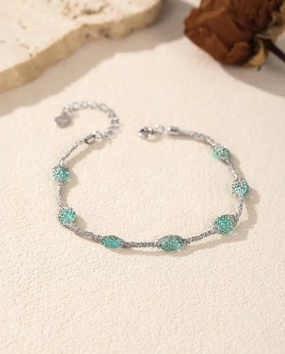 Zirkonia Armband in 925 Sterling Zilver - versie met groene zirkonia naast een travertijnplaat en een gedroogde roos
